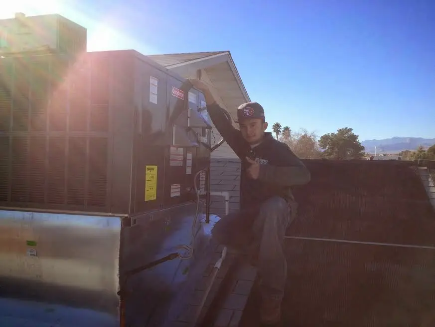 HVAC technician performing AC Tune-Up on a rooftop unit in Newton